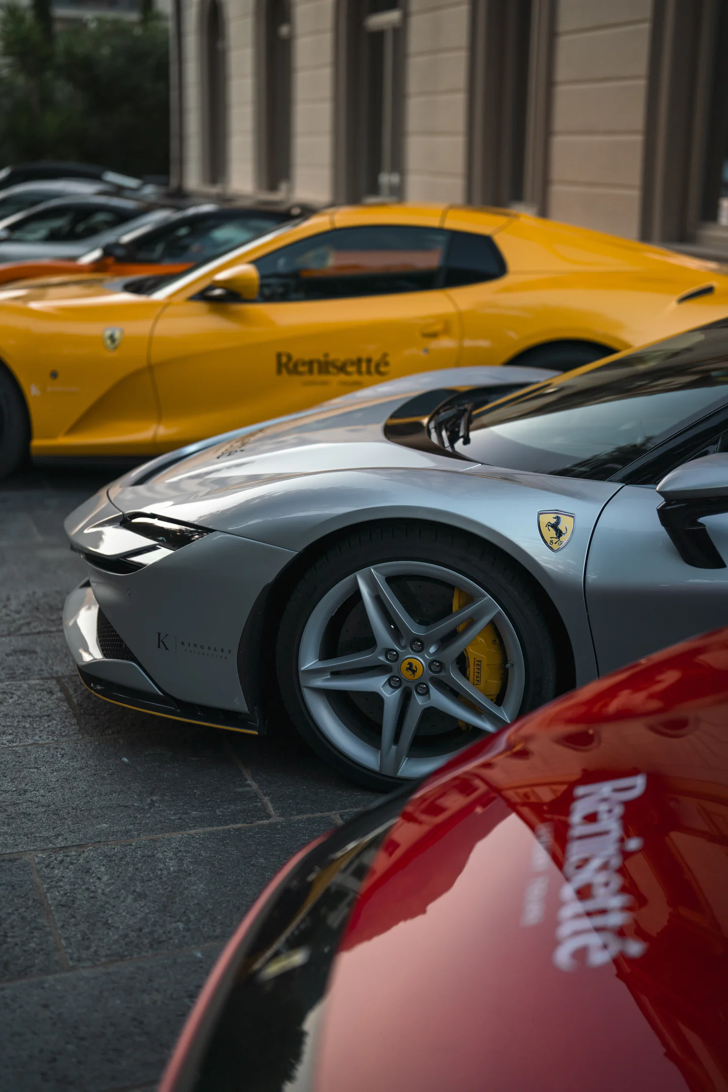Renisetté-branded yellow Ferrari, silver Ferrari and red supercar parked in a row